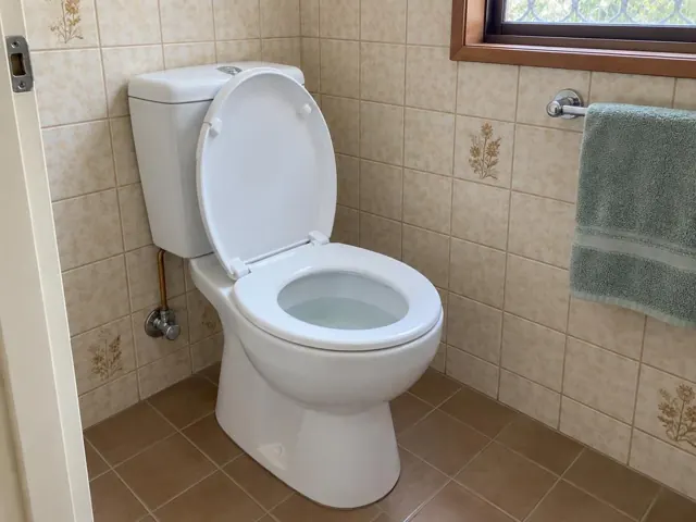 Clean white toilet in a tiled bathroom with towel rail and window in Quakers Hill
